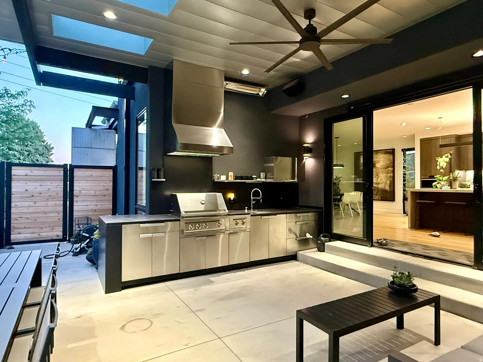 Outdoor kitchen featuring stainless steel cabinetry, integrated grill, range hood, and sink