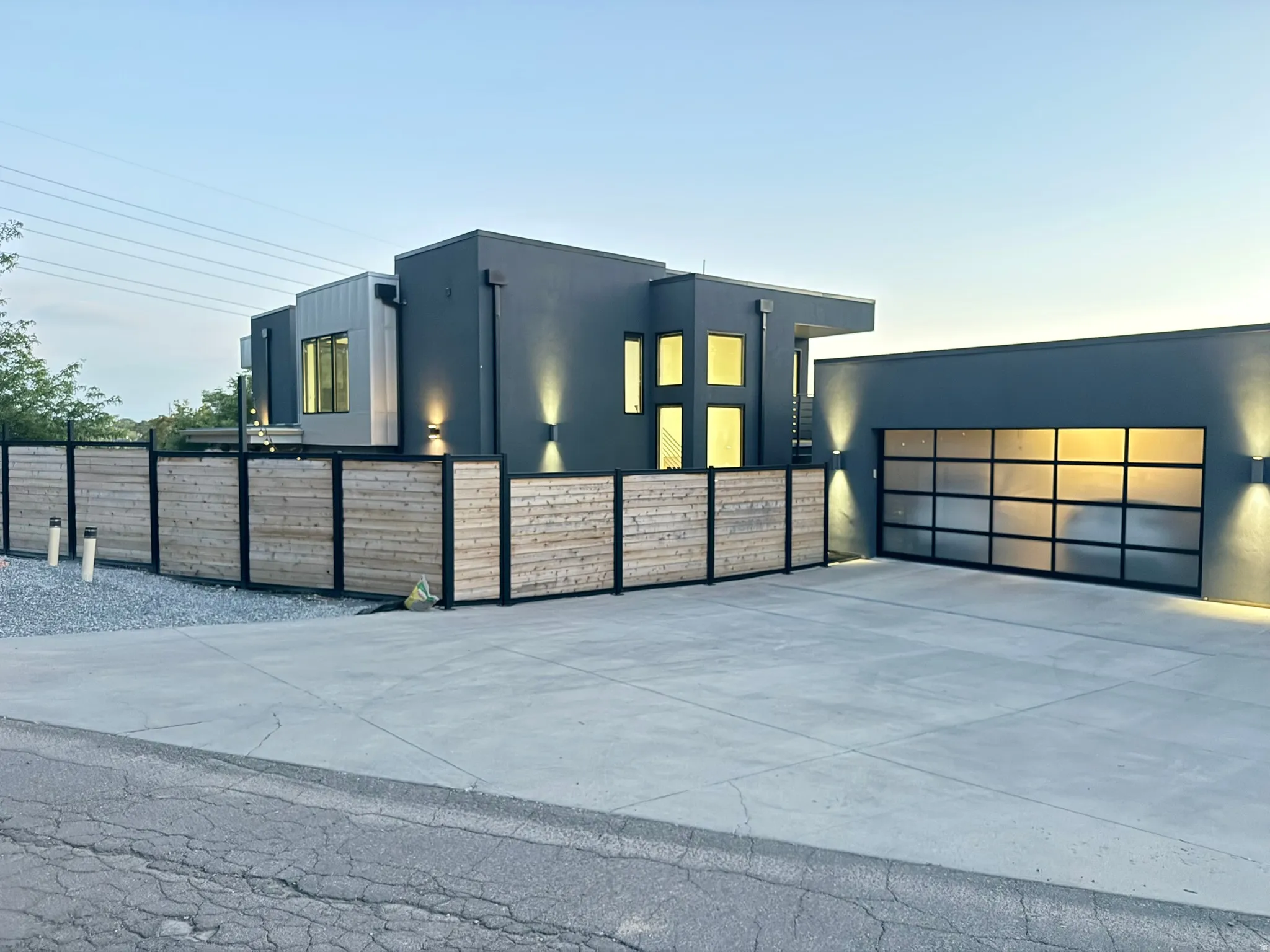 Modern architectural design featuring a multi-tone exterior, a clear-panel garage door, and a perimeter fence with wood slats and black metal framing