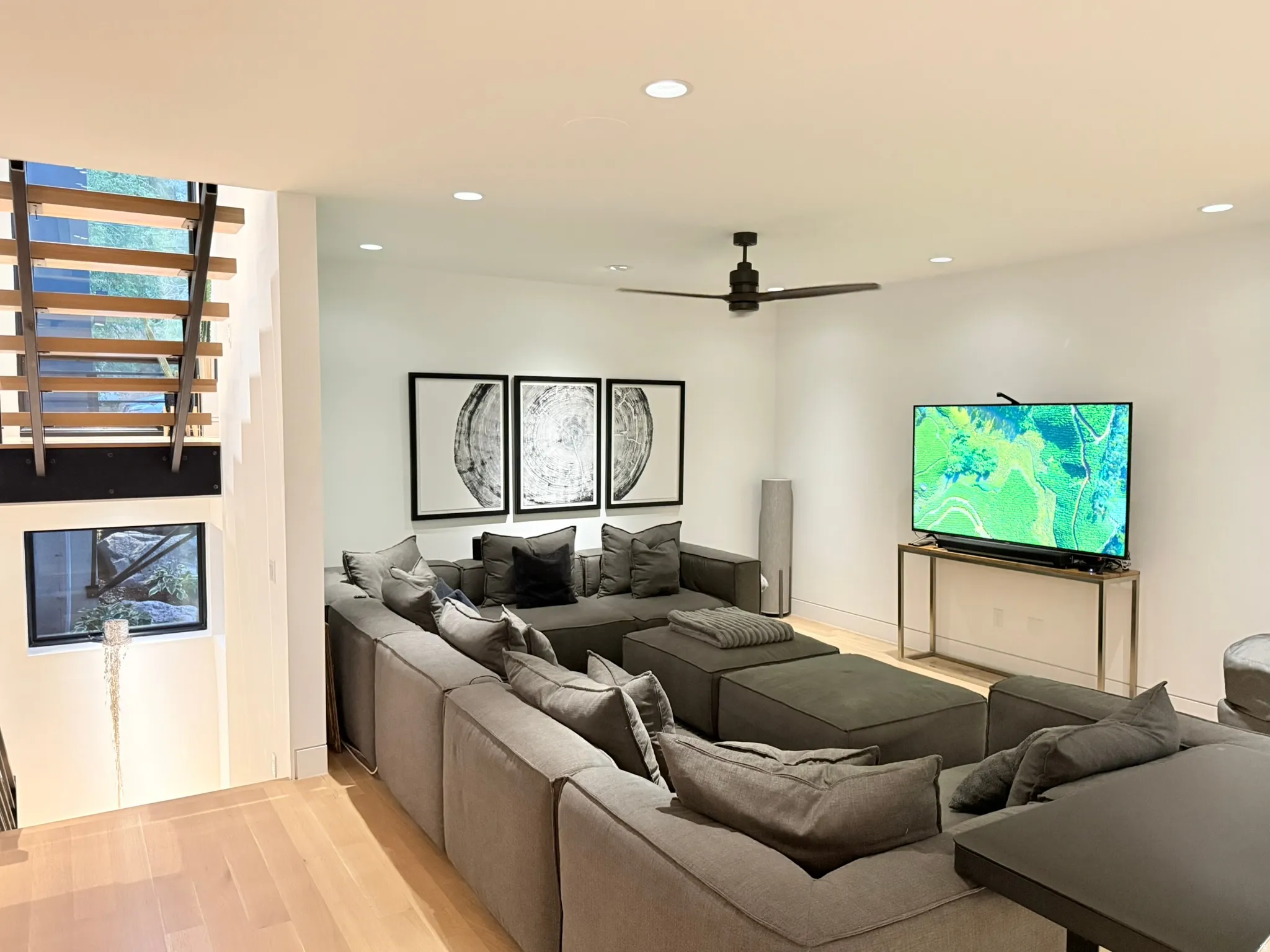 Spacious living area featuring light wood-finish flooring, recessed lighting, and a modern ceiling fan