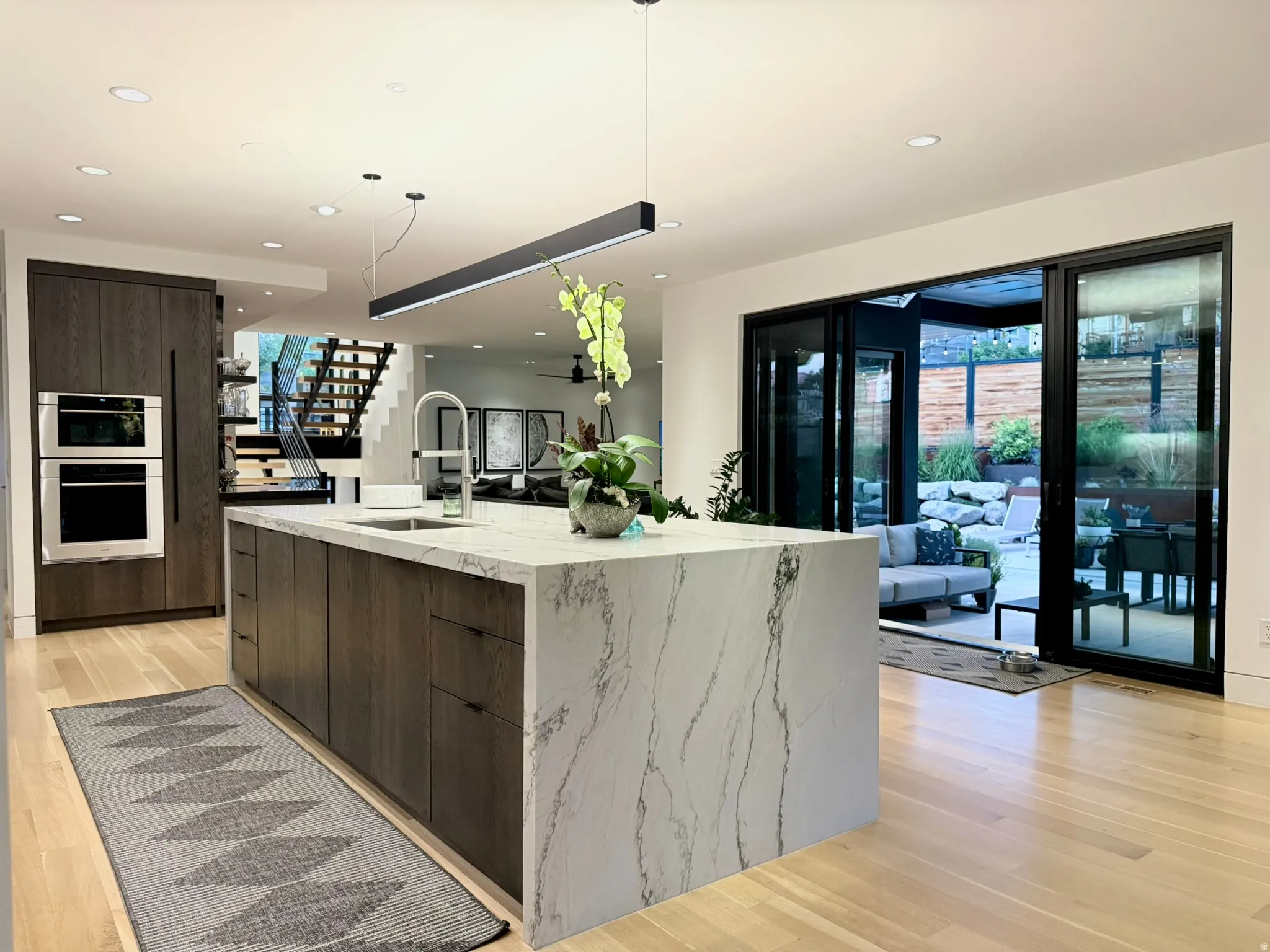 Kitchen with a waterfall island featuring a stone countertop, an integrated sink, and an extendable faucet