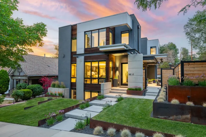 Contemporary multi-level exterior featuring varied cladding, extensive window placement, a concrete walkway, and landscaped front yard with decorative retaining elements