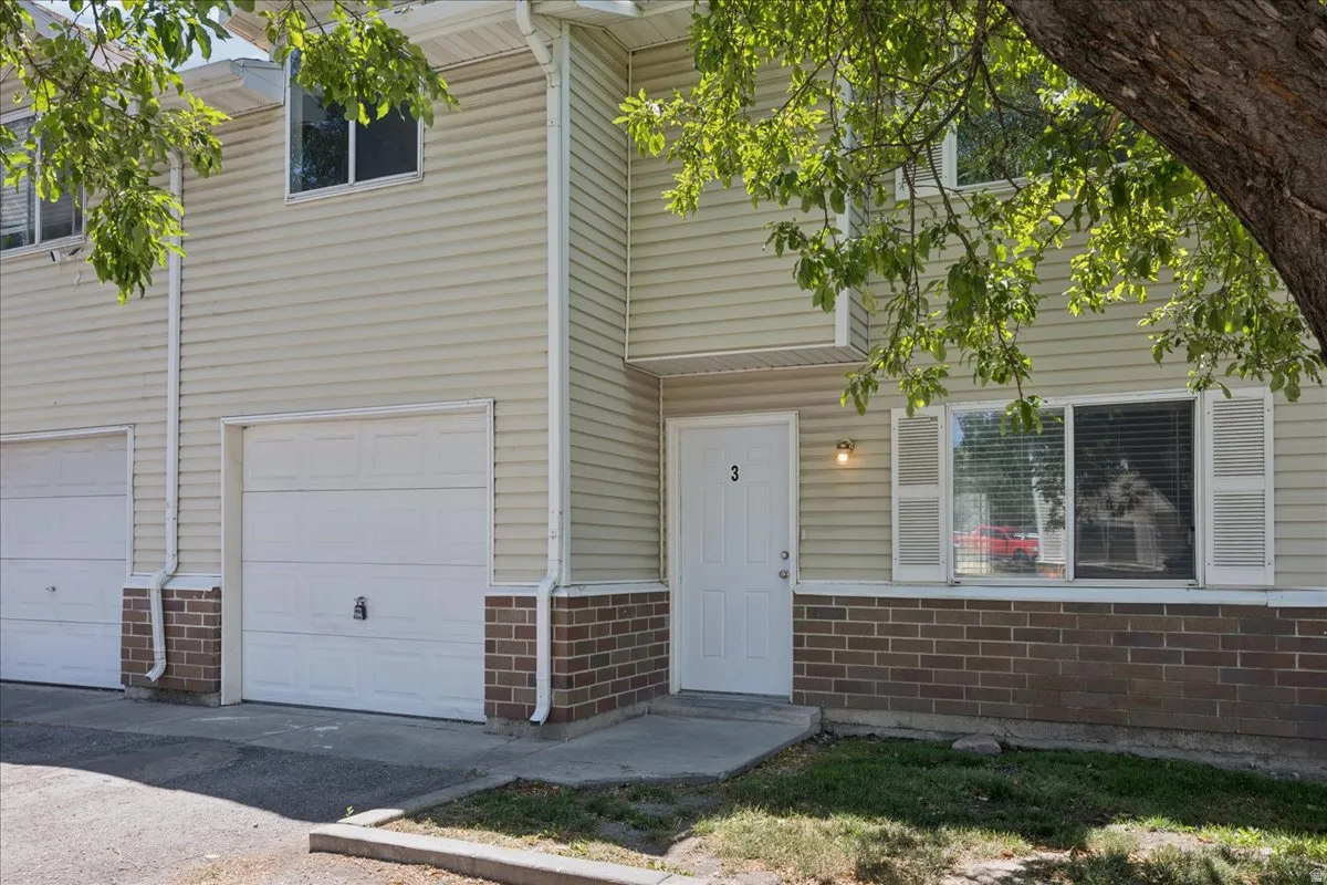 Townhome exterior featuring light-colored siding and a brick-finish foundation