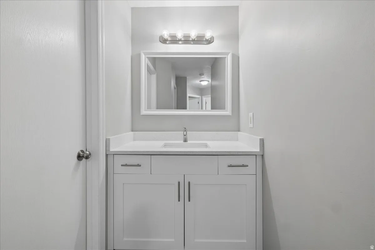 Bathroom vanity featuring a white shaker-style cabinet, integrated sink, and light-colored countertop
