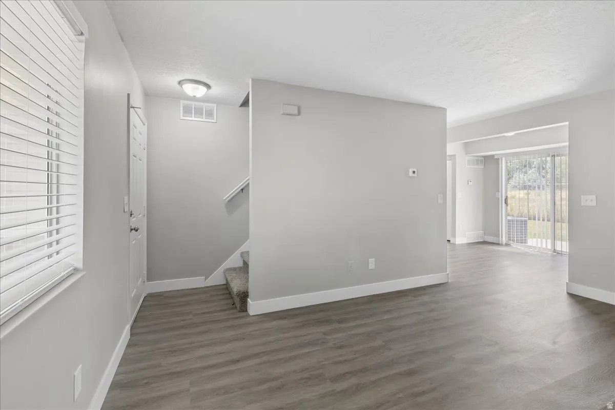 Open-concept living area featuring wood-finish flooring, light grey wall tones, white trim, and a sliding glass door leading to the exterior