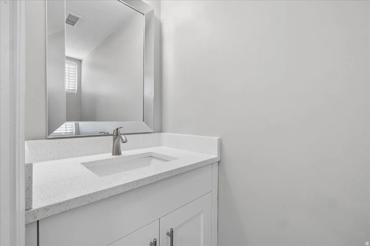 Bathroom vanity featuring a rectangular inset sink, brushed nickel faucet, and a light-toned countertop