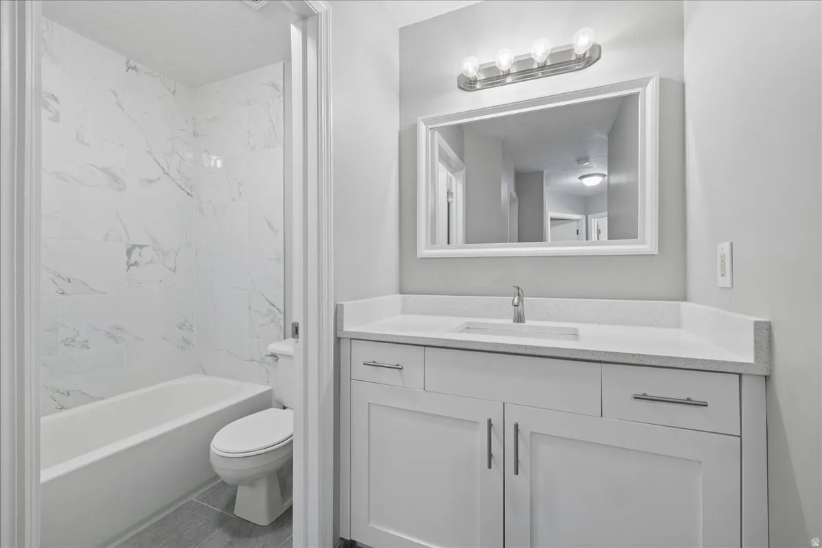 Contemporary bathroom featuring a white vanity with shaker-style cabinetry, a solid surface countertop, and a rectangular undermount sink