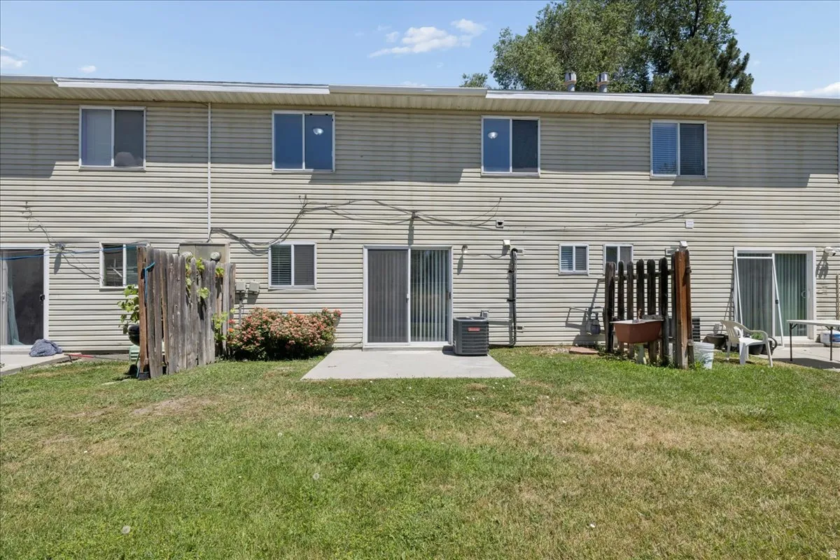 Rear exterior featuring light-toned horizontal siding, multiple windows, and two sliding glass doors providing outdoor access