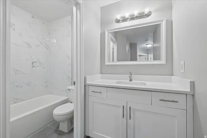 Contemporary bathroom featuring a white vanity with shaker-style cabinetry, a solid surface countertop, and a rectangular undermount sink