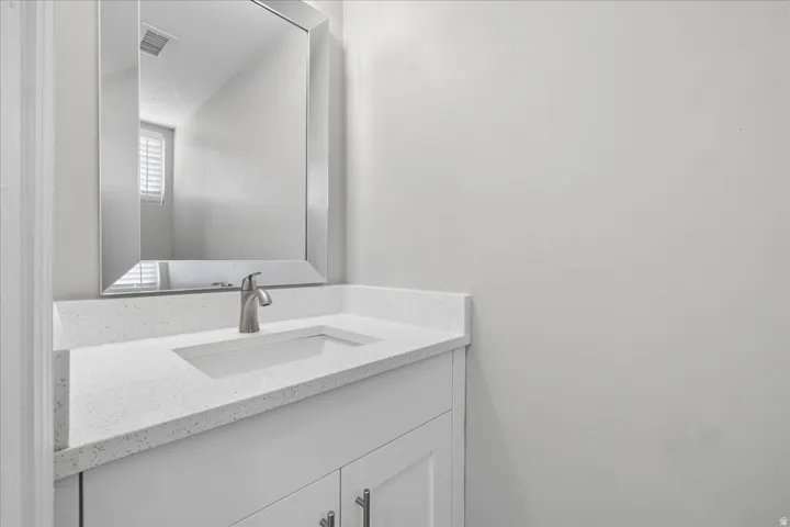 Bathroom vanity featuring a rectangular inset sink, brushed nickel faucet, and a light-toned countertop