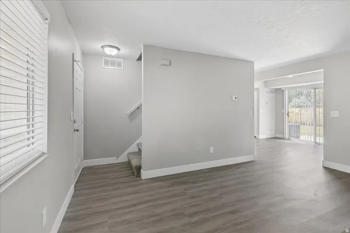 Open-concept living area featuring wood-finish flooring, light grey wall tones, white trim, and a sliding glass door leading to the exterior