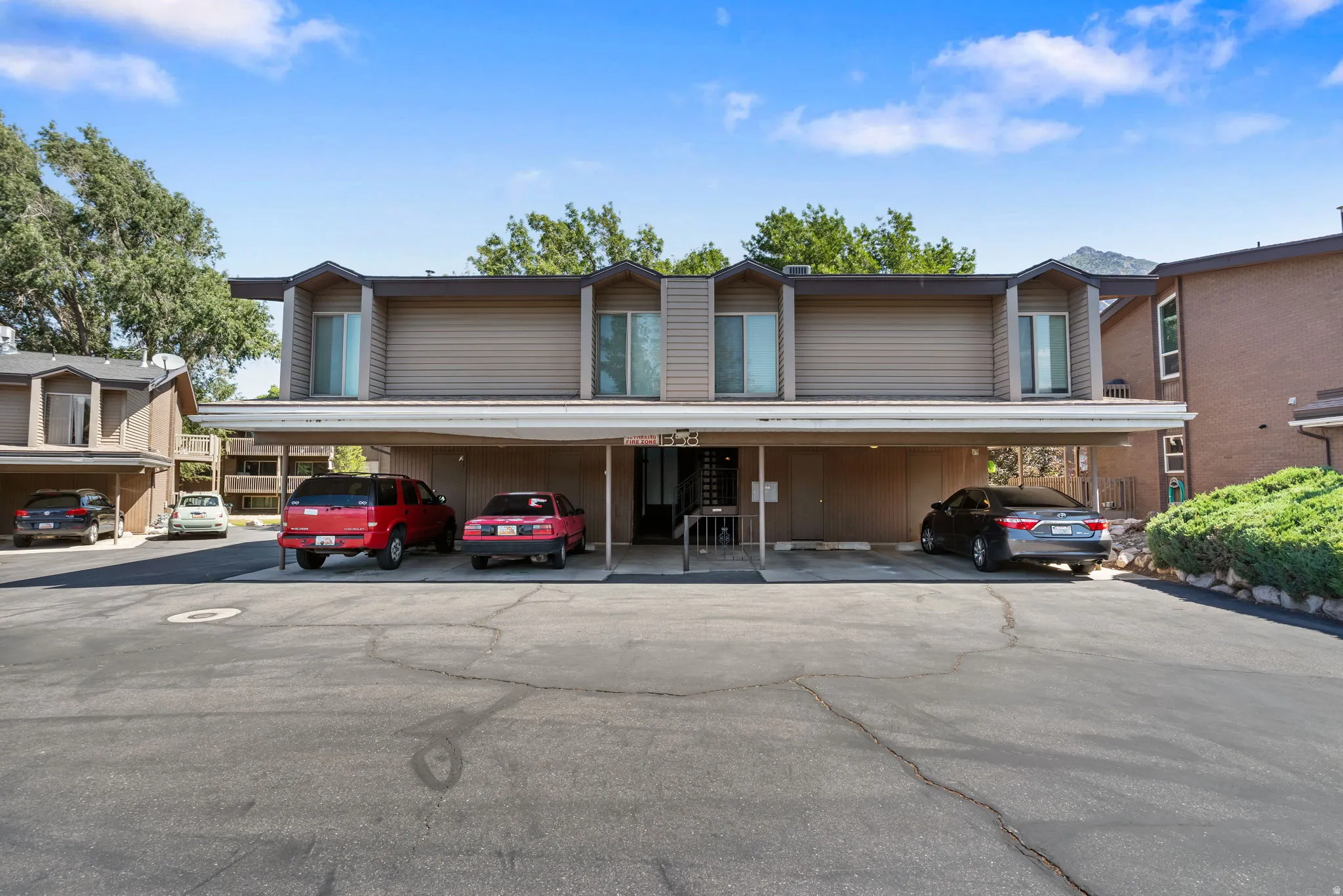 Multi-level residential building featuring tan horizontal siding and multiple dormer windows