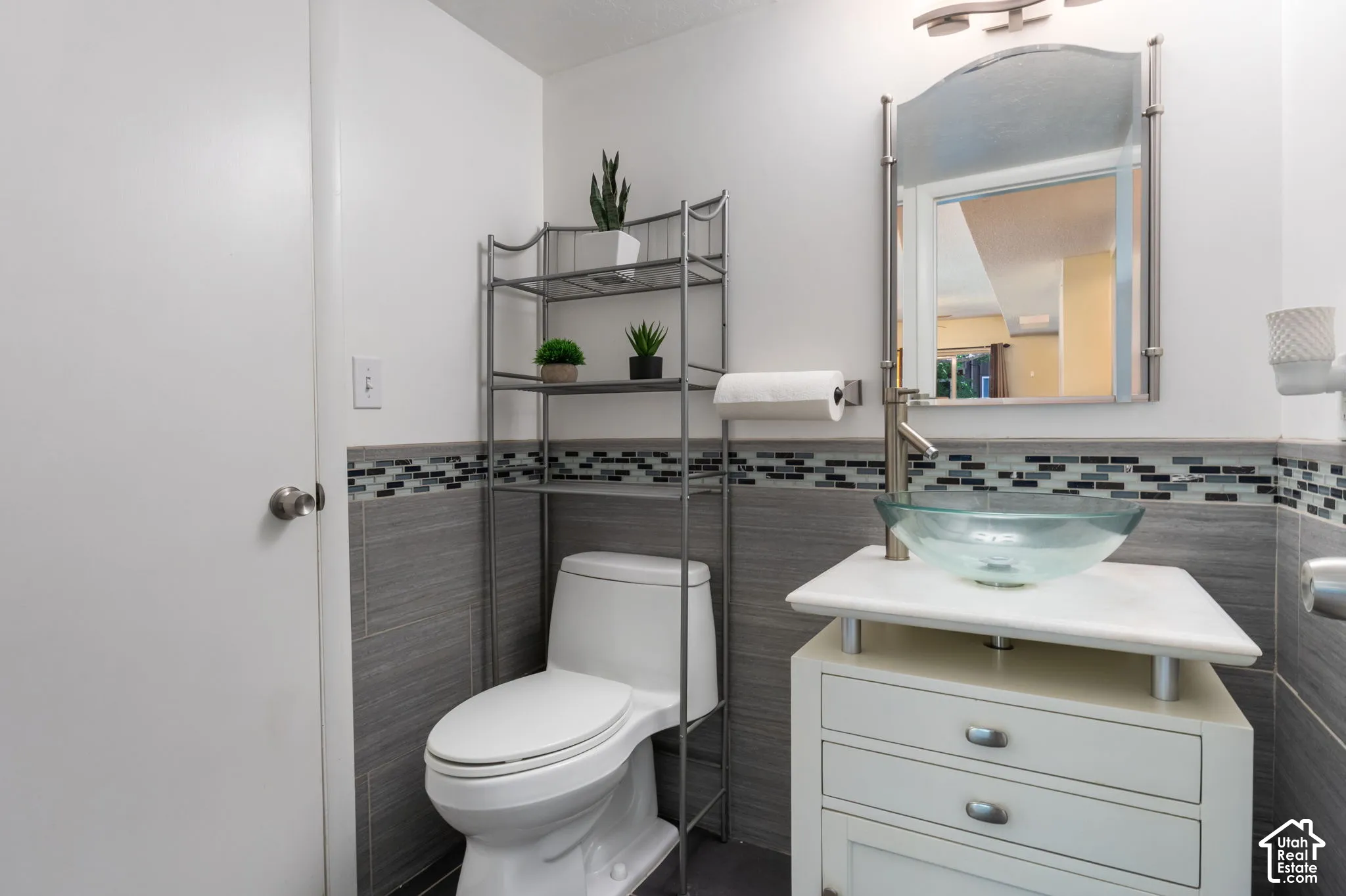 Bathroom featuring a modern vessel sink, white vanity with drawer storage, and a tile accent wall