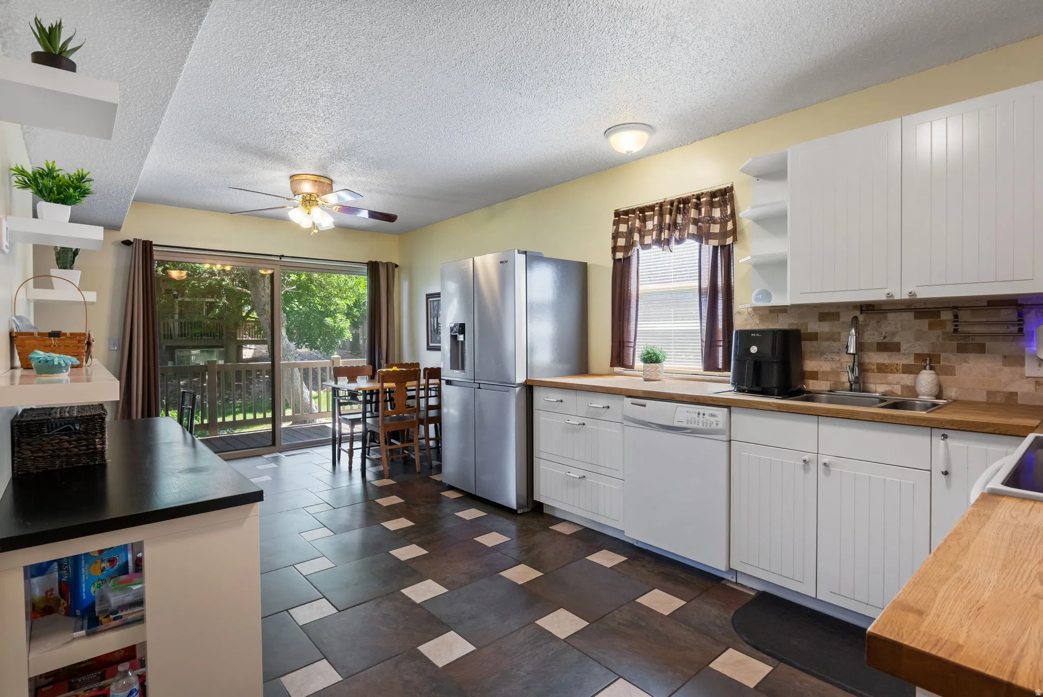 Kitchen featuring white cabinetry with beadboard detailing, wood-finish countertops, stainless steel appliances, and a tiled backsplash