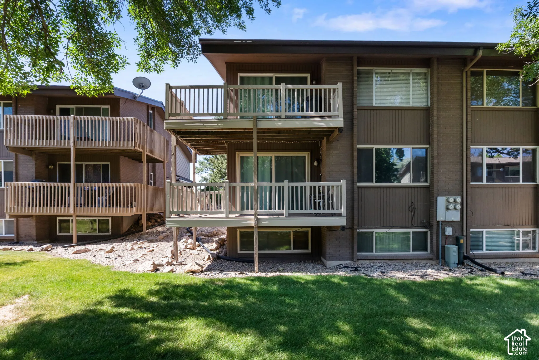 Multi-level residential building featuring wood-sided exterior and multiple private balconies with wood railings
