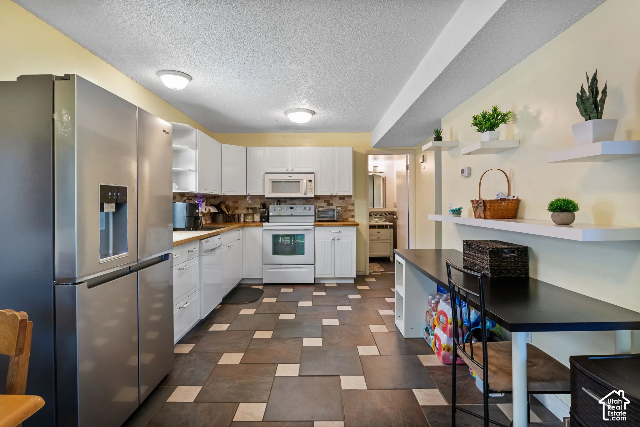 Kitchen featuring white cabinetry, wood-finish countertops, and a full suite of white appliances including a range, microwave, and dishwasher