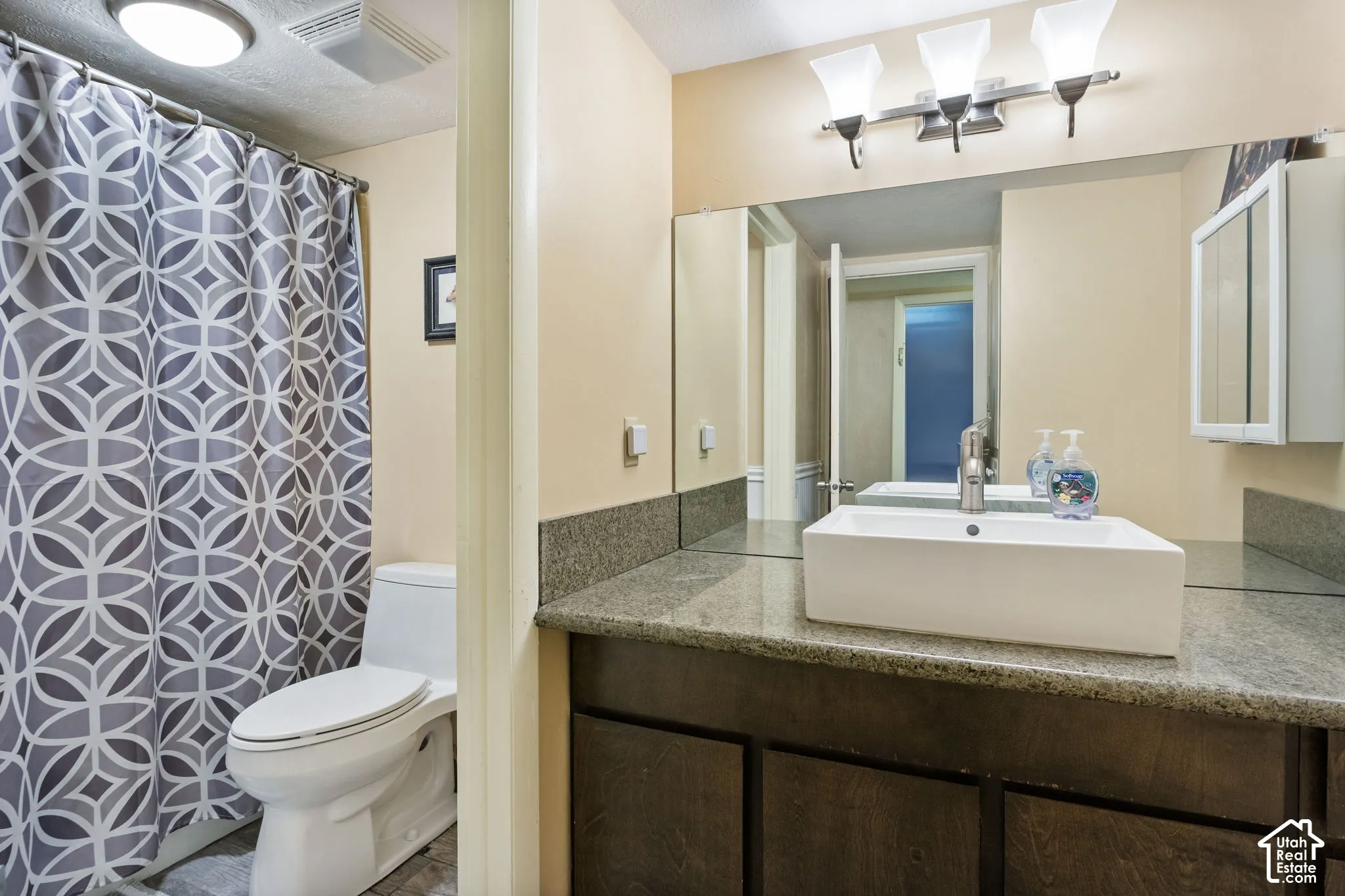 Modern bathroom featuring a rectangular vessel sink, granite countertop, wood-finish vanity, and full-width mirror