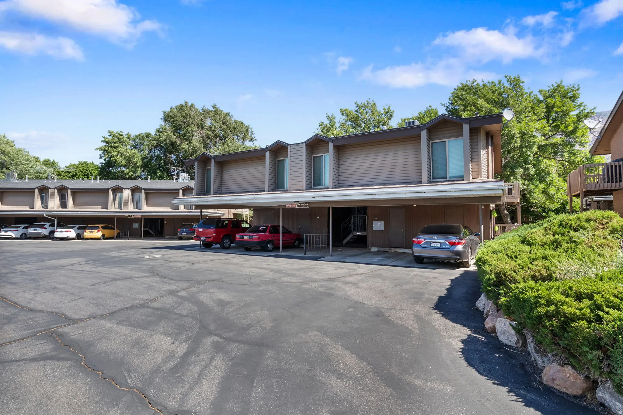 Multi-unit residential complex featuring covered parking spaces and a large paved lot
