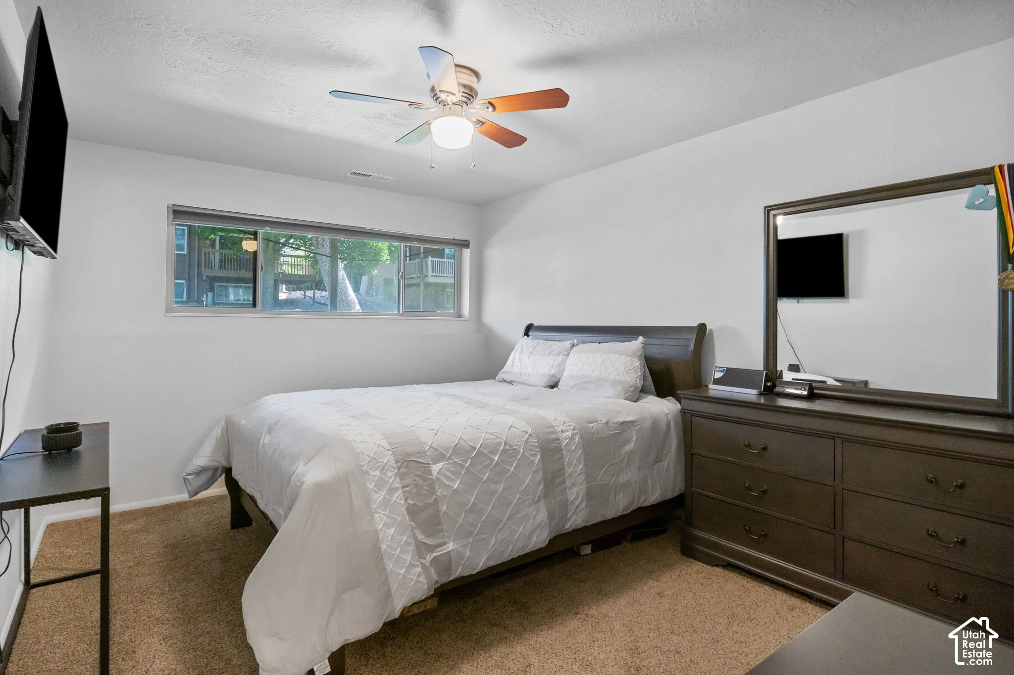 Carpeted room featuring a wide window, ceiling fan with light fixture, and white walls