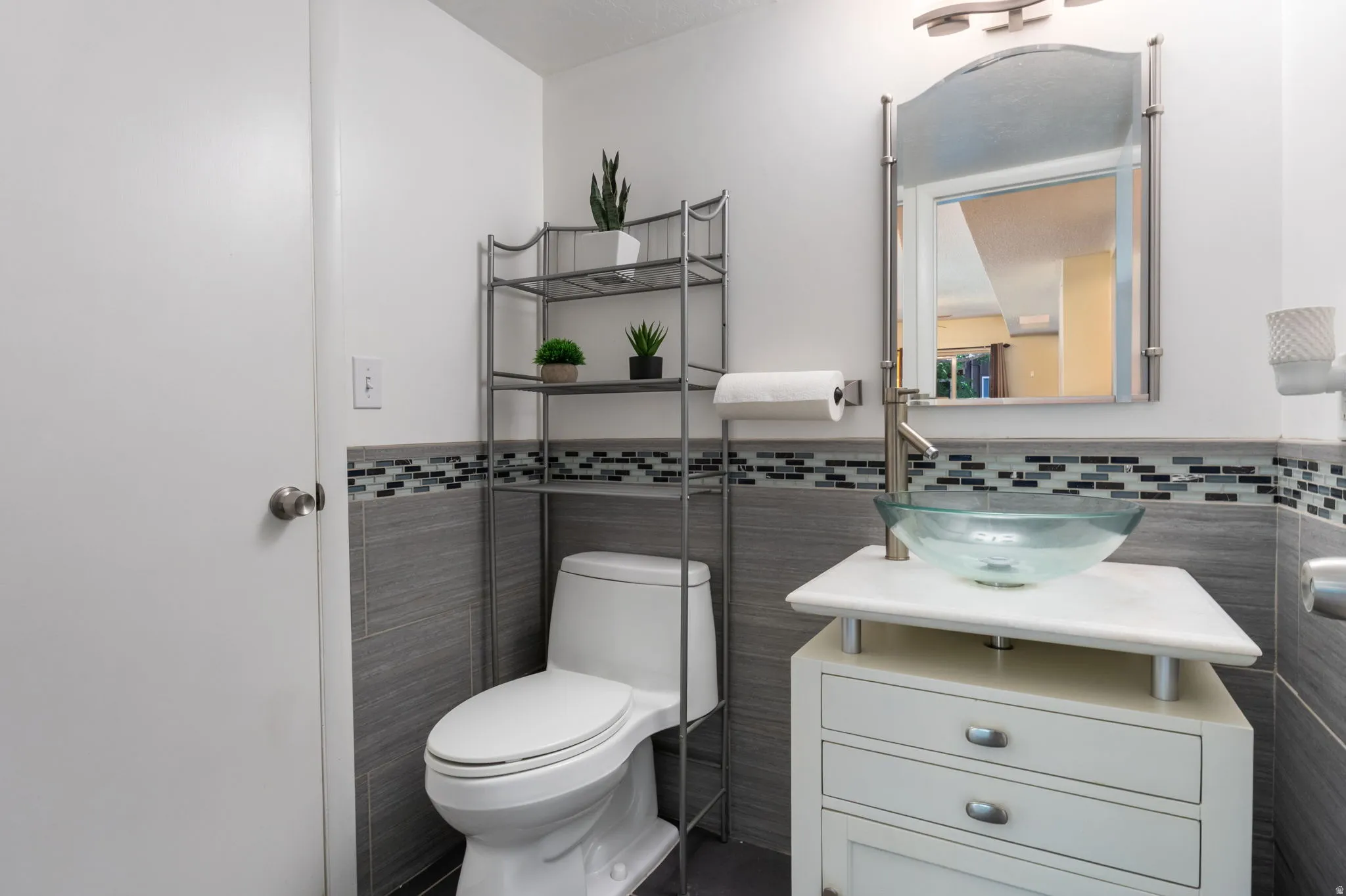 Bathroom featuring a modern vessel sink, white vanity with drawer storage, and a tile accent wall