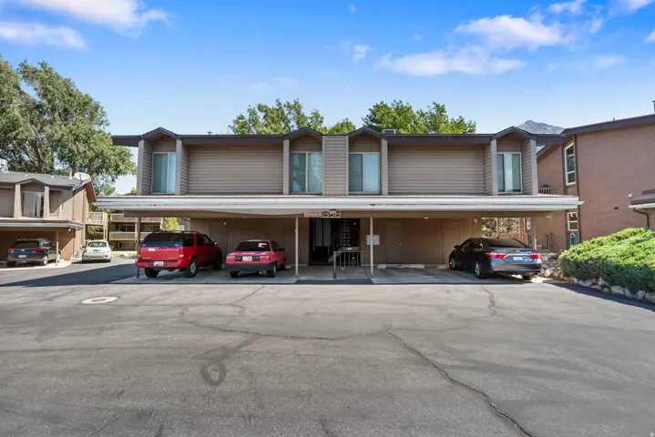 Multi-level residential building featuring tan horizontal siding and multiple dormer windows