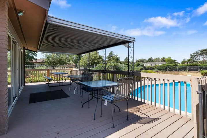 Expansive outdoor deck featuring a covered patio, wood-finish decking, and a perimeter railing