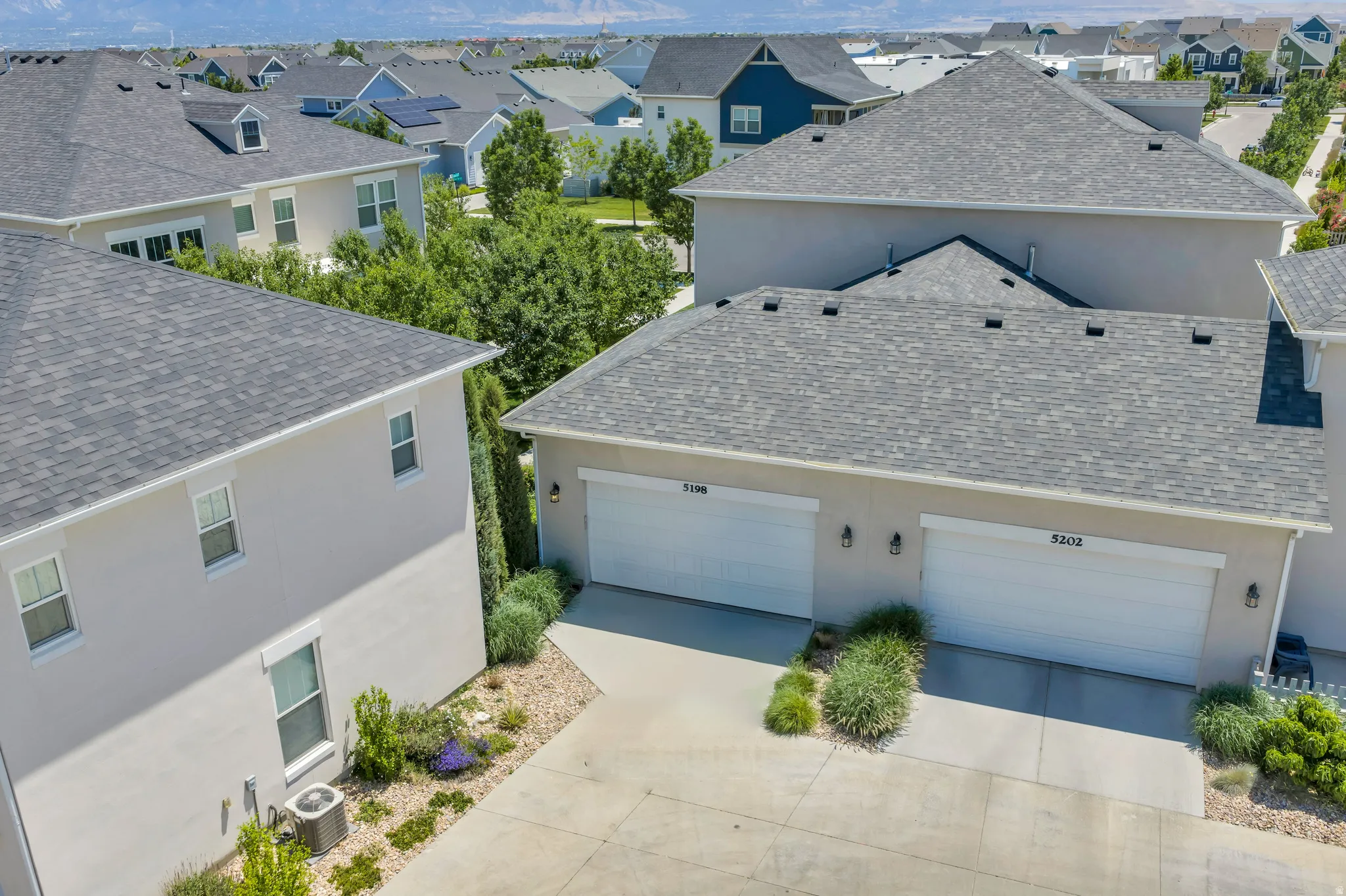 Two-story stucco home with a two-car garage, featuring a gray asphalt shingle roof