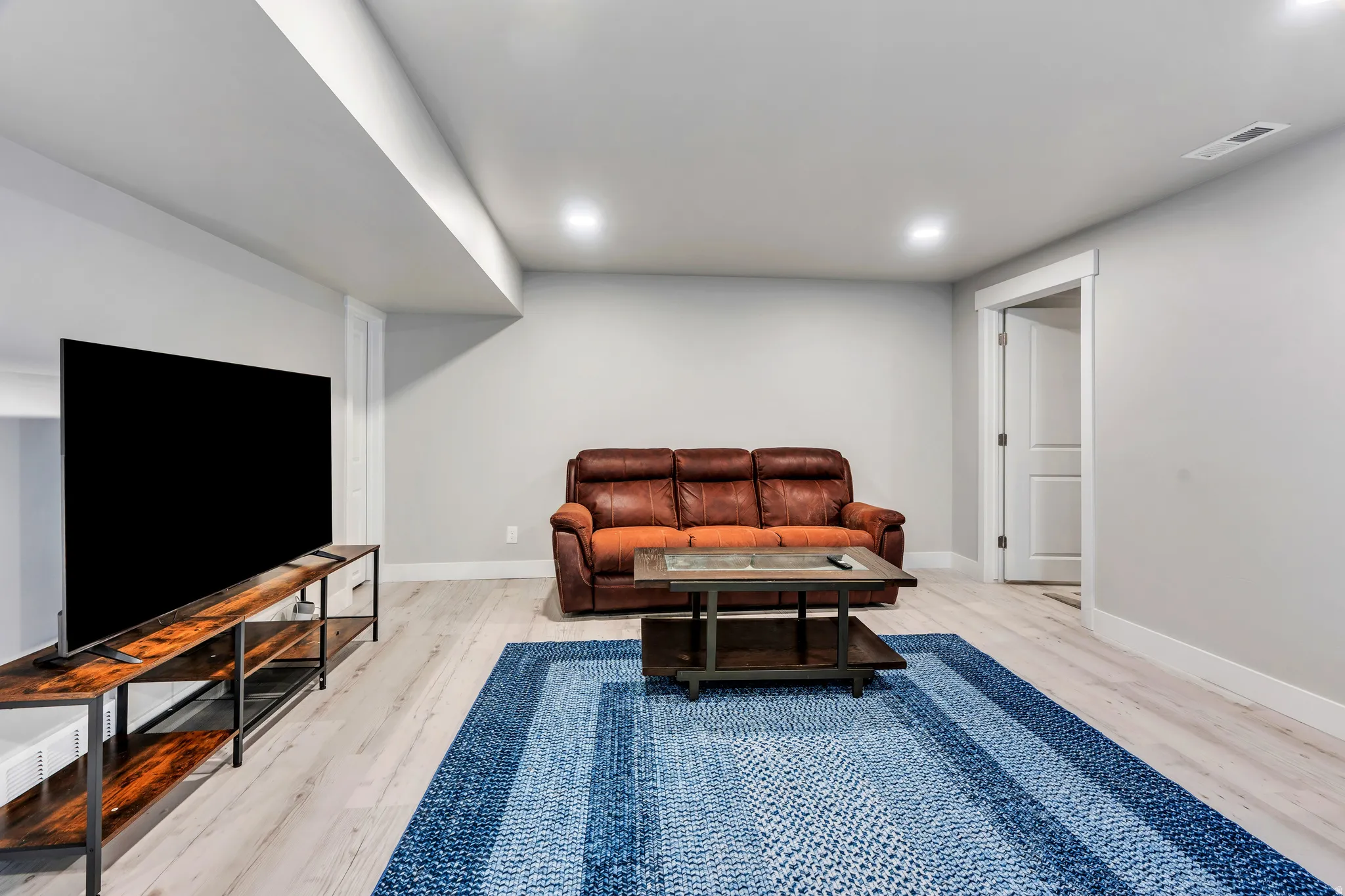 Spacious room featuring light wood-finish flooring, recessed lighting, and a white trim package