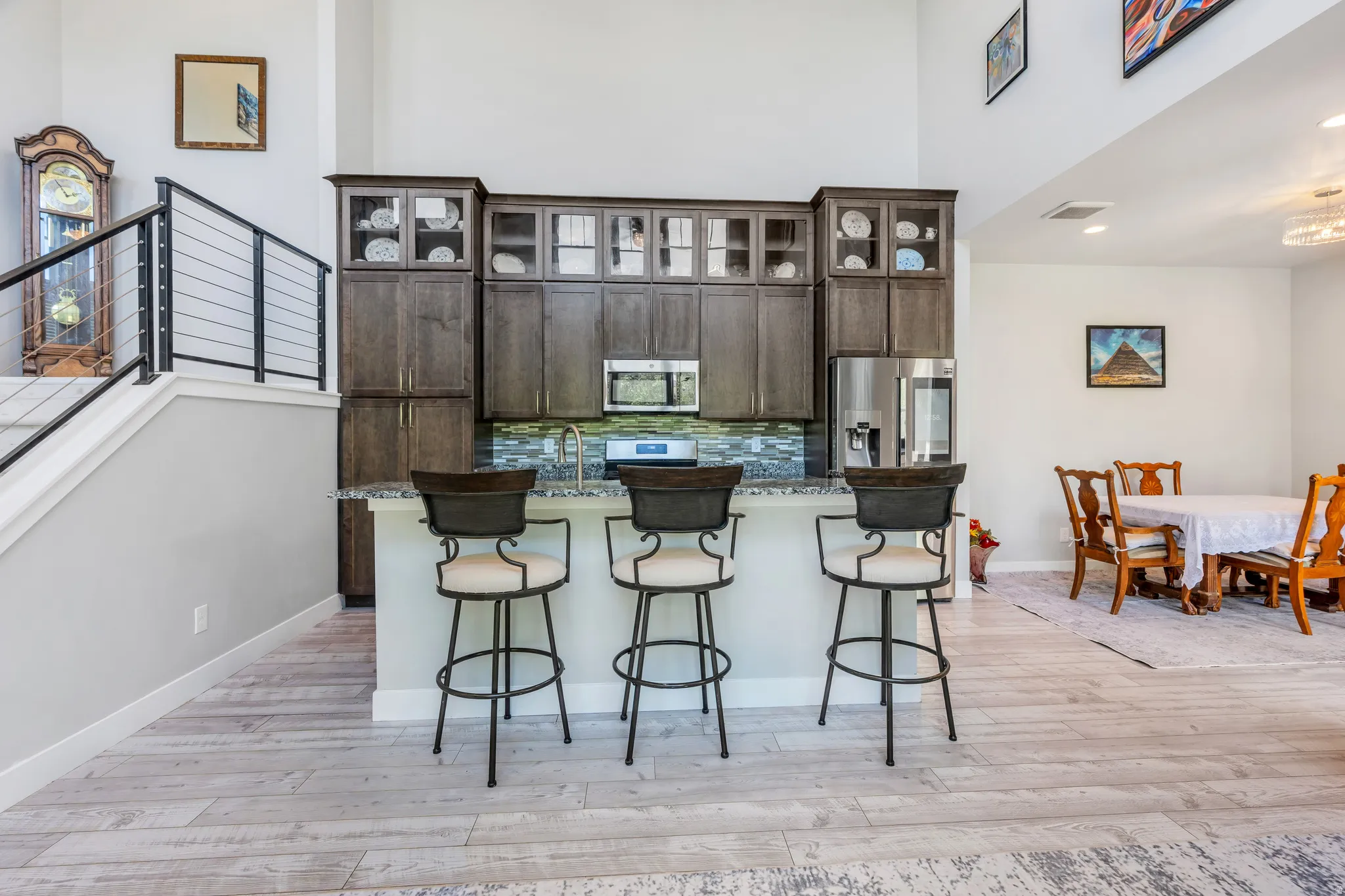 Open-concept living space with wood-finish flooring, a kitchen island with seating, dark wood cabinetry, and a stainless steel appliance suite