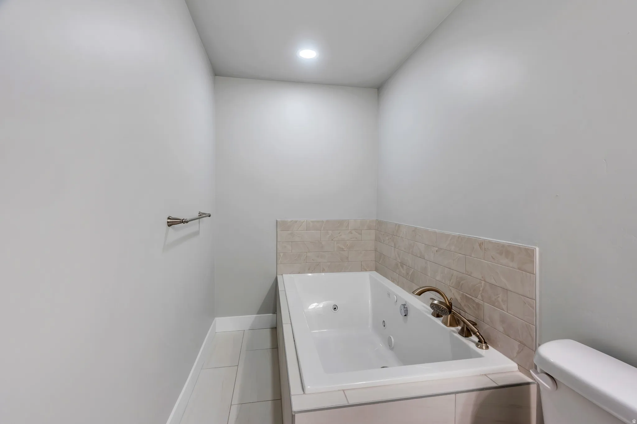 Jetted tub with bronze-finish fixtures, complemented by light-toned subway tile surround