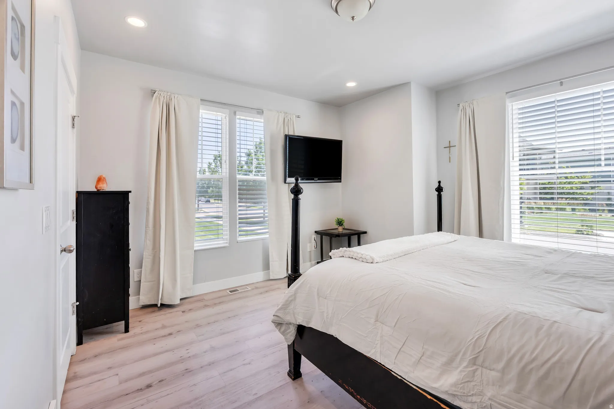 Spacious room featuring light wood-finish flooring, recessed lighting, and a prominent window