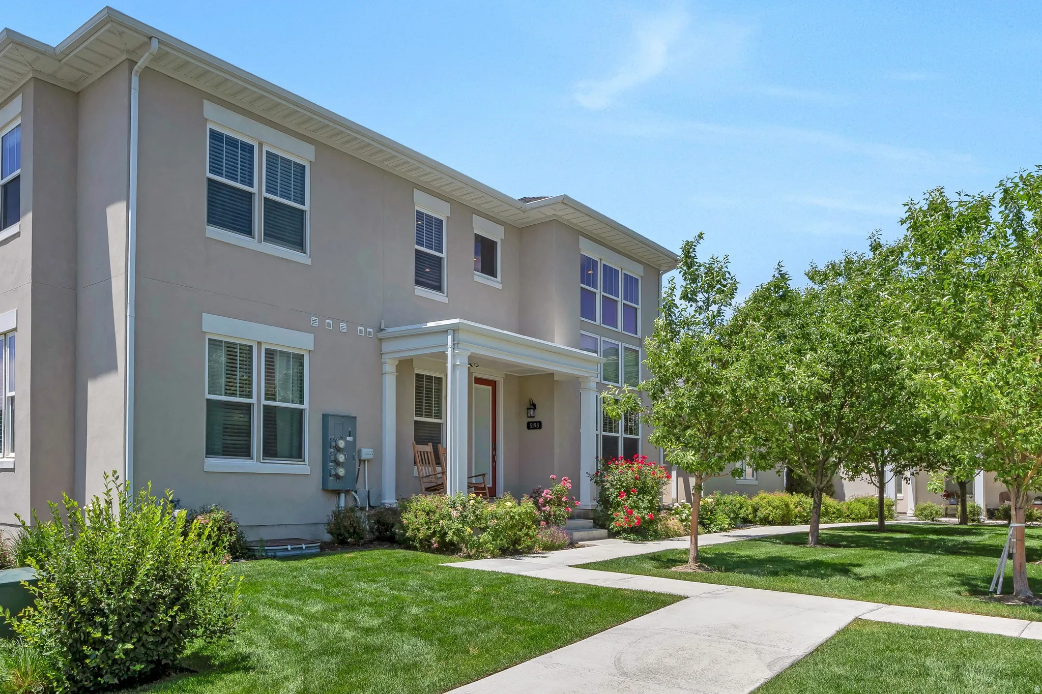 Stucco exterior featuring white trim, multiple windows, and a covered porch entry