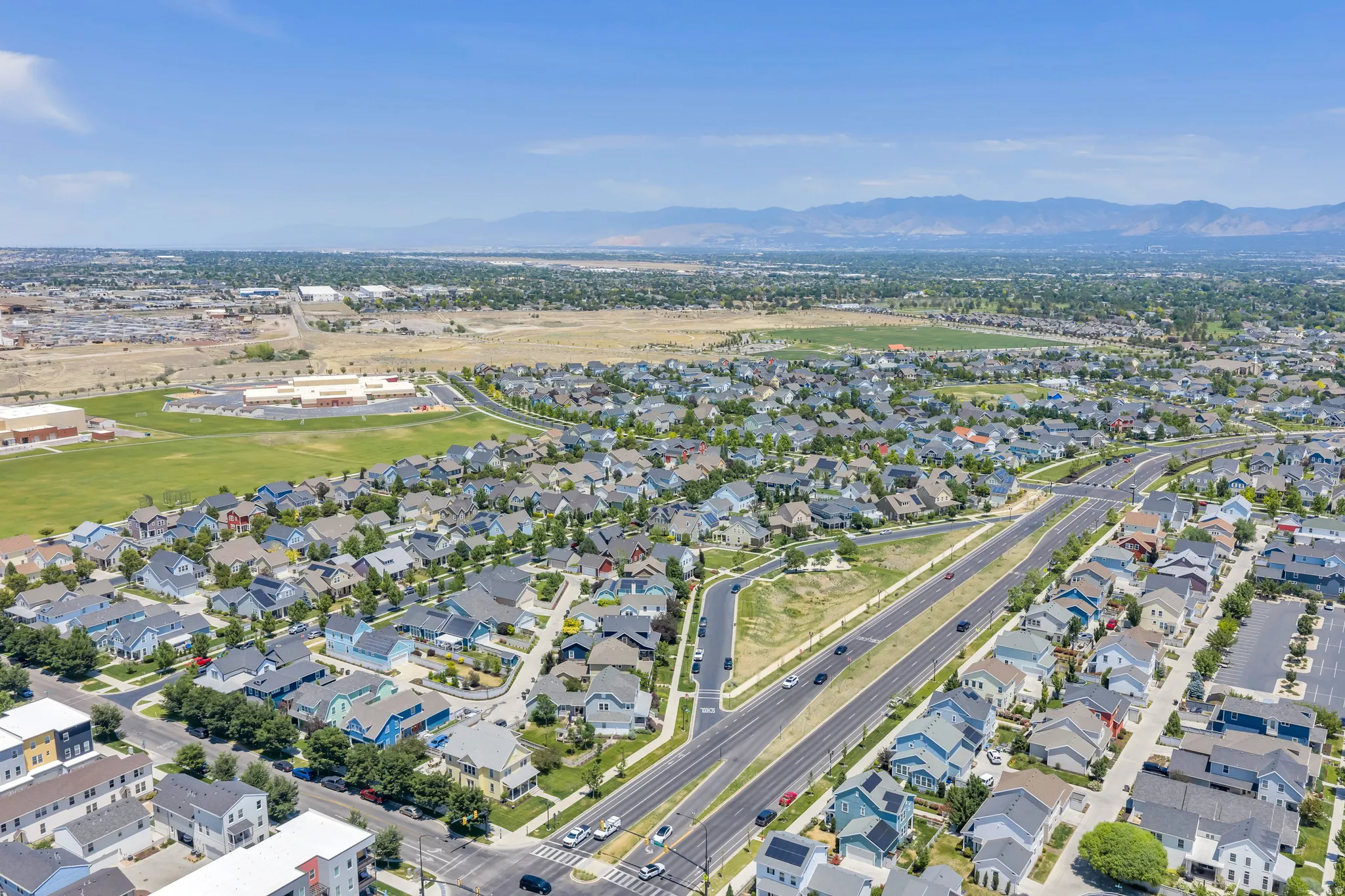 Expansive residential development with a variety of single-family homes and multi-story buildings, featuring tree-lined streets and well-maintained roadways