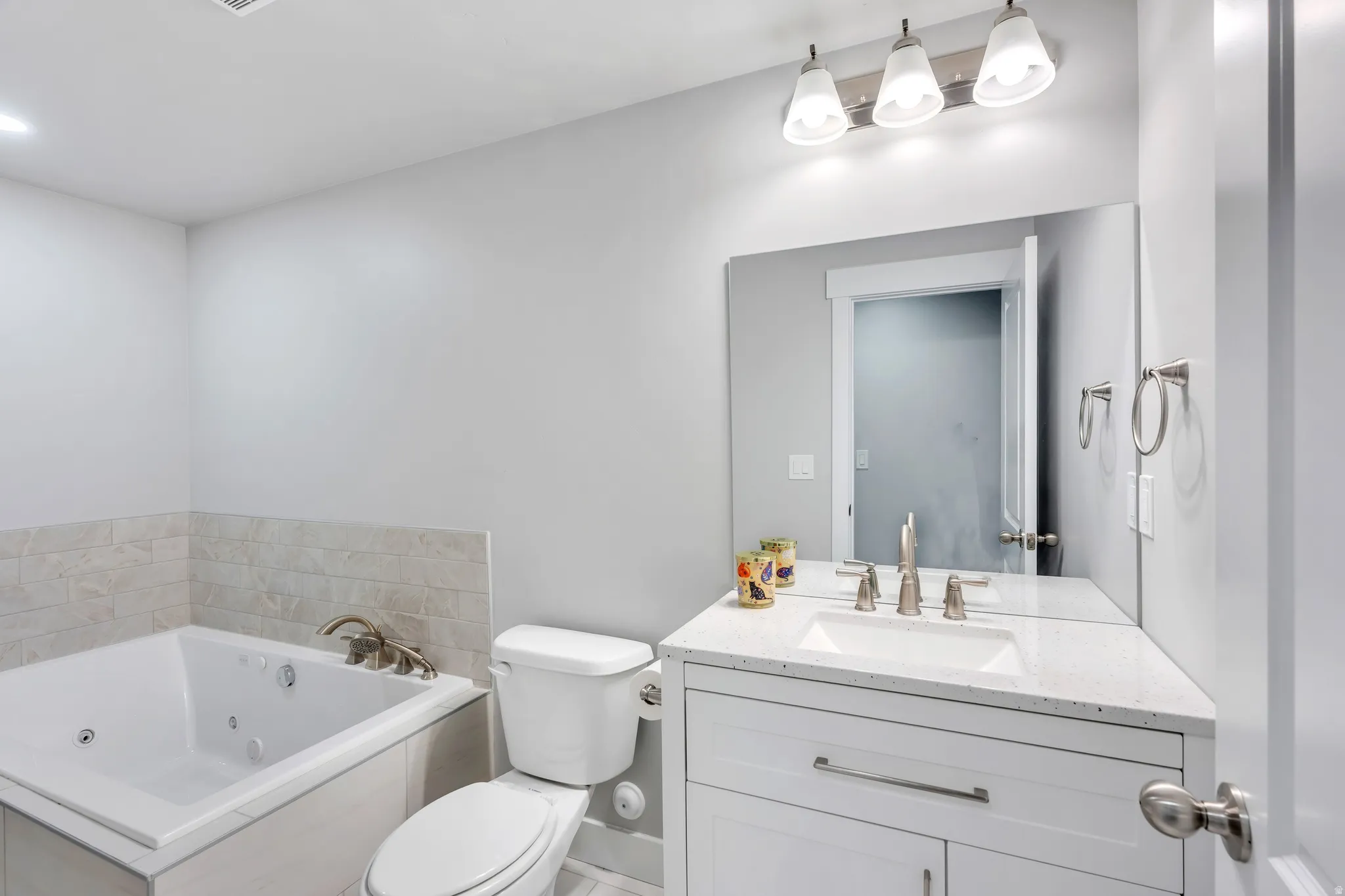 Modern bathroom featuring a corner vanity with a built-in sink, a quartz-finish countertop, and brushed nickel hardware