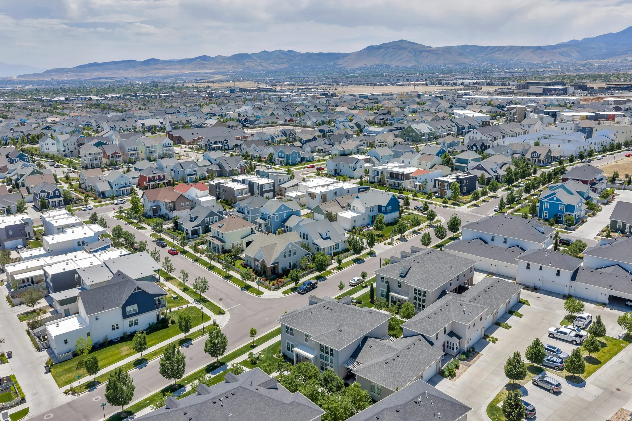 Expansive residential community featuring diverse architectural styles, tree-lined streets, and mountain backdrops