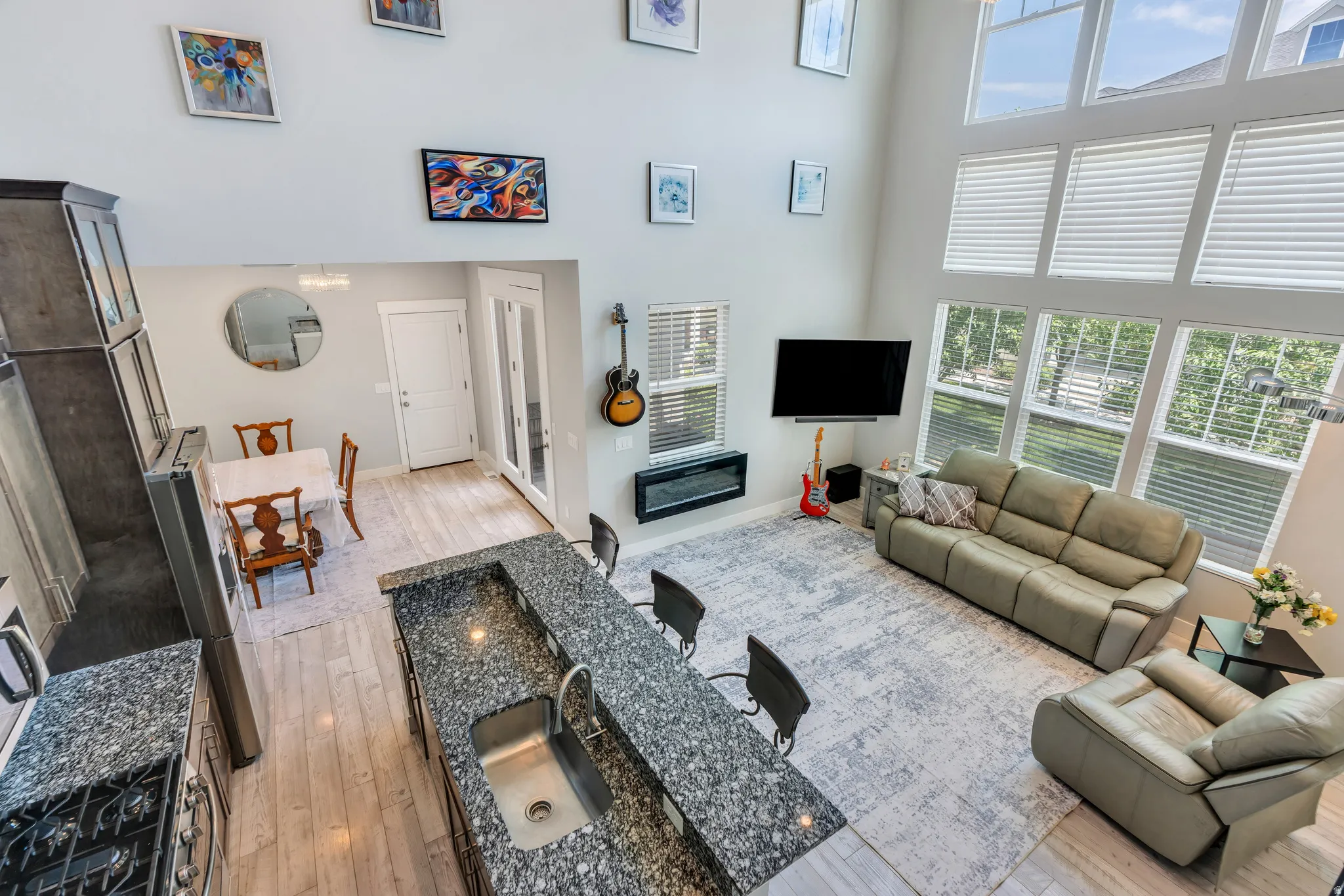 Two-story living area with high ceilings, multiple large windows providing abundant natural light, and a built-in electric fireplace