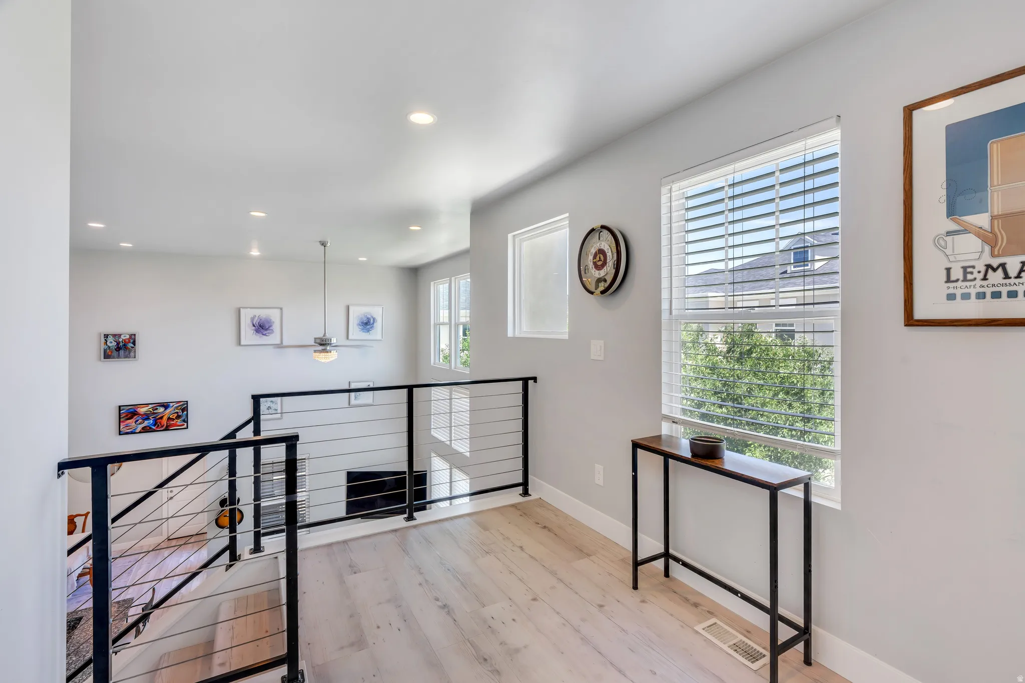 Upper-level hallway with light wood-finish flooring, recessed lighting, and a contemporary cable railing system