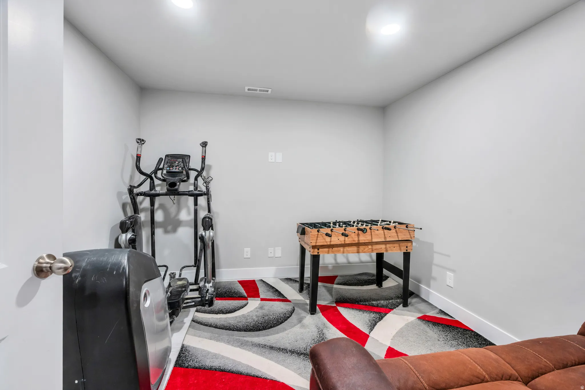 Room featuring light gray walls, recessed lighting, and a vibrant area rug with red, gray, and black patterns