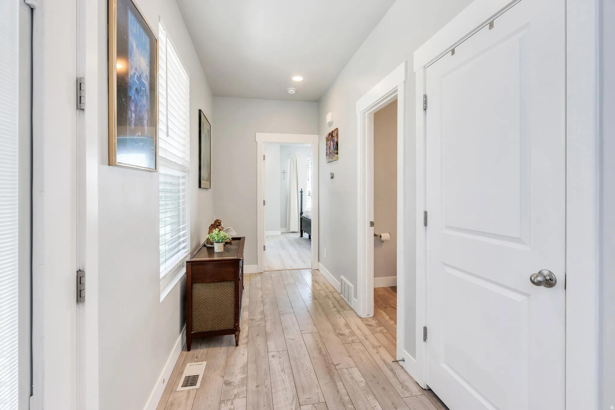 Hallway featuring wood-finish flooring, white paneled doors, and light gray wall paint