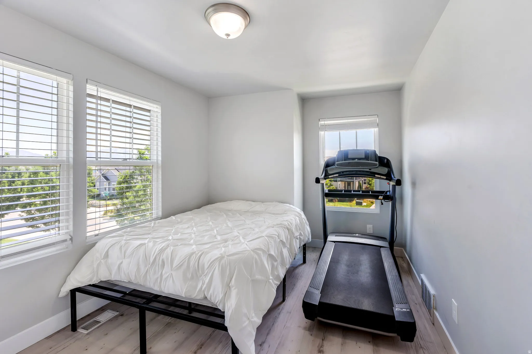 Bright room featuring light wood-finish flooring and three windows for ample natural light
