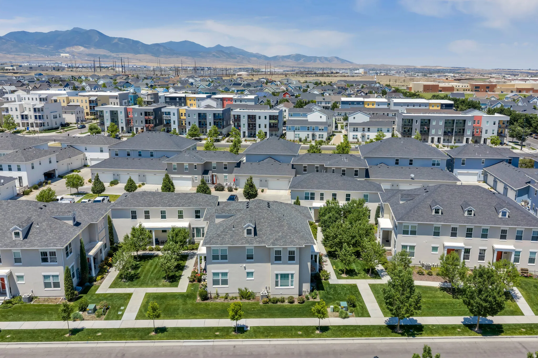 Expansive aerial perspective showcasing a residential community with diverse architectural styles, featuring detached homes, townhomes, and multi-story buildings