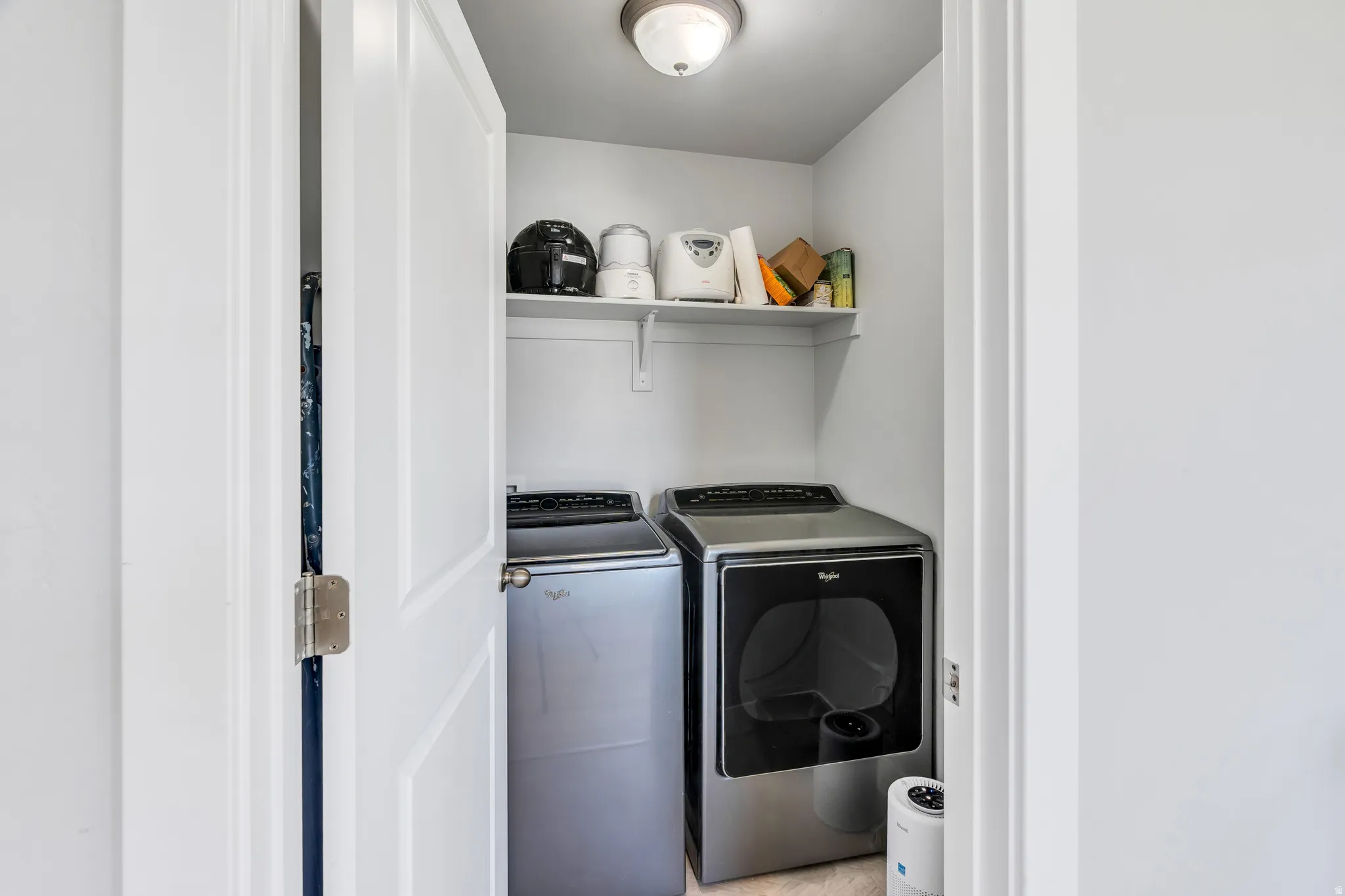 Dedicated laundry area featuring a washer and dryer, an overhead shelf for storage, and ceiling-mounted lighting