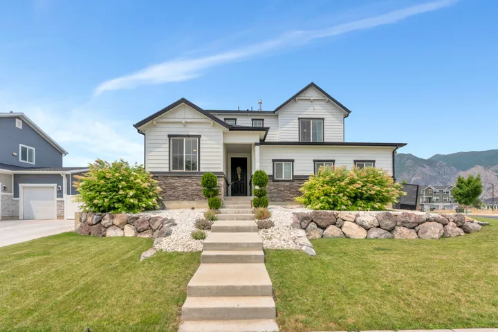 Contemporary two-story residence featuring light siding with dark trim accents and a stone veneer foundation