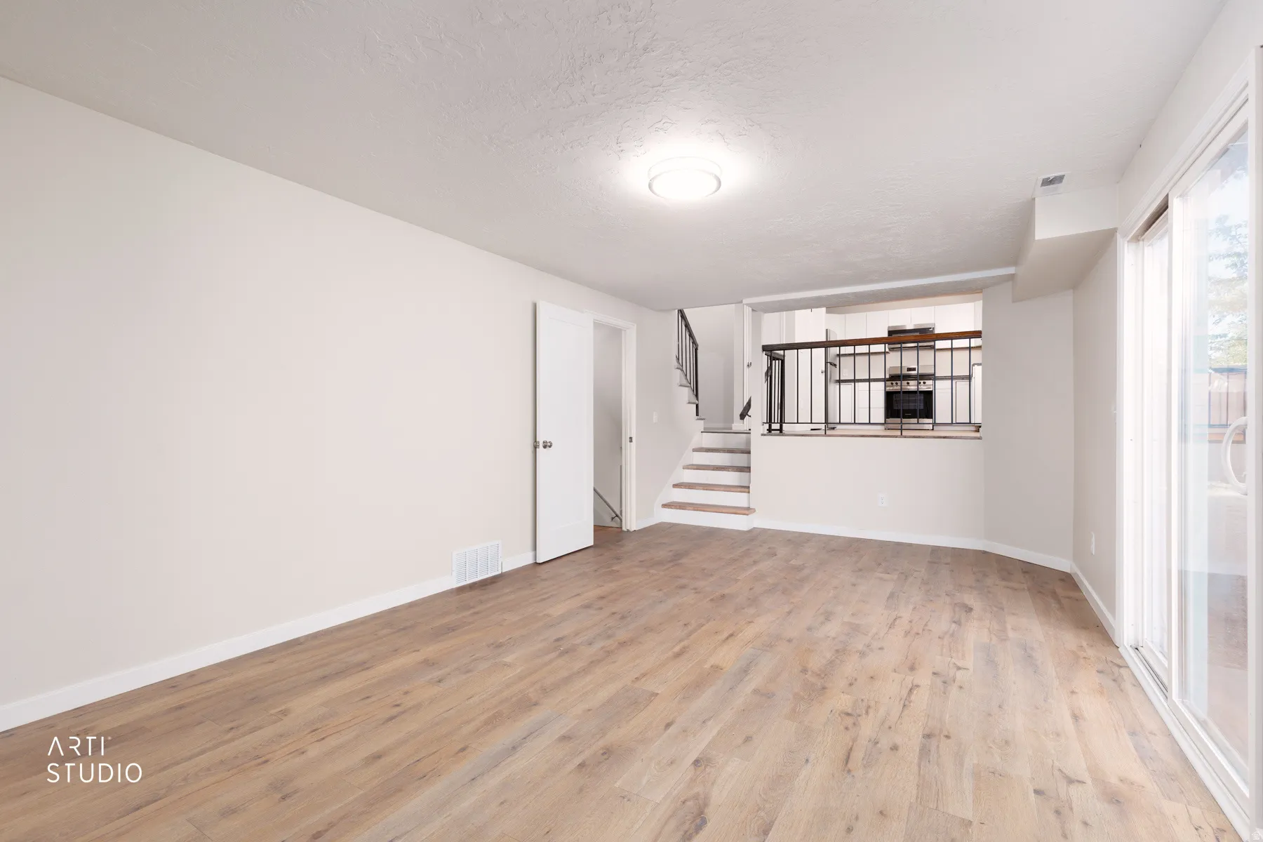 Spacious living area featuring wood-finish flooring, light neutral wall paint, and a built-in ceiling light fixture