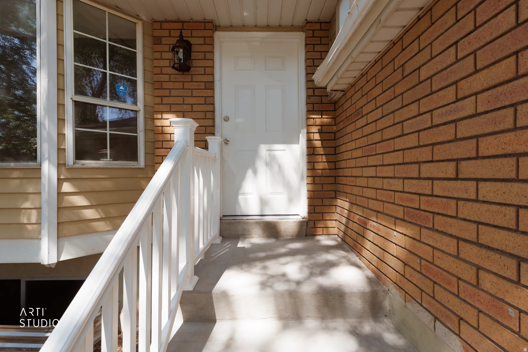 Front entry featuring a white door, brick exterior, vinyl siding, concrete steps, and white railings