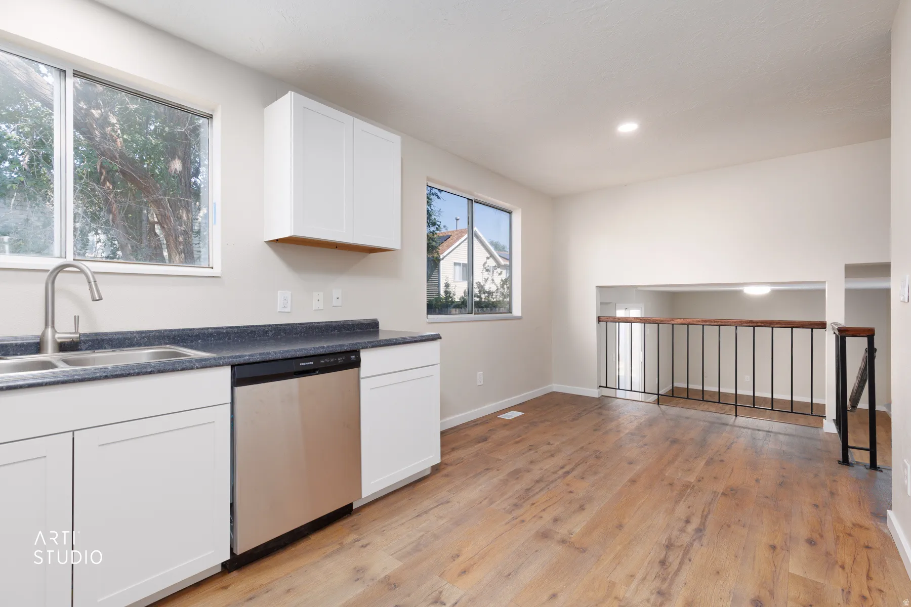 Modern kitchen space featuring white shaker cabinetry, a stainless steel dishwasher, and a dual basin sink with a brushed nickel faucet