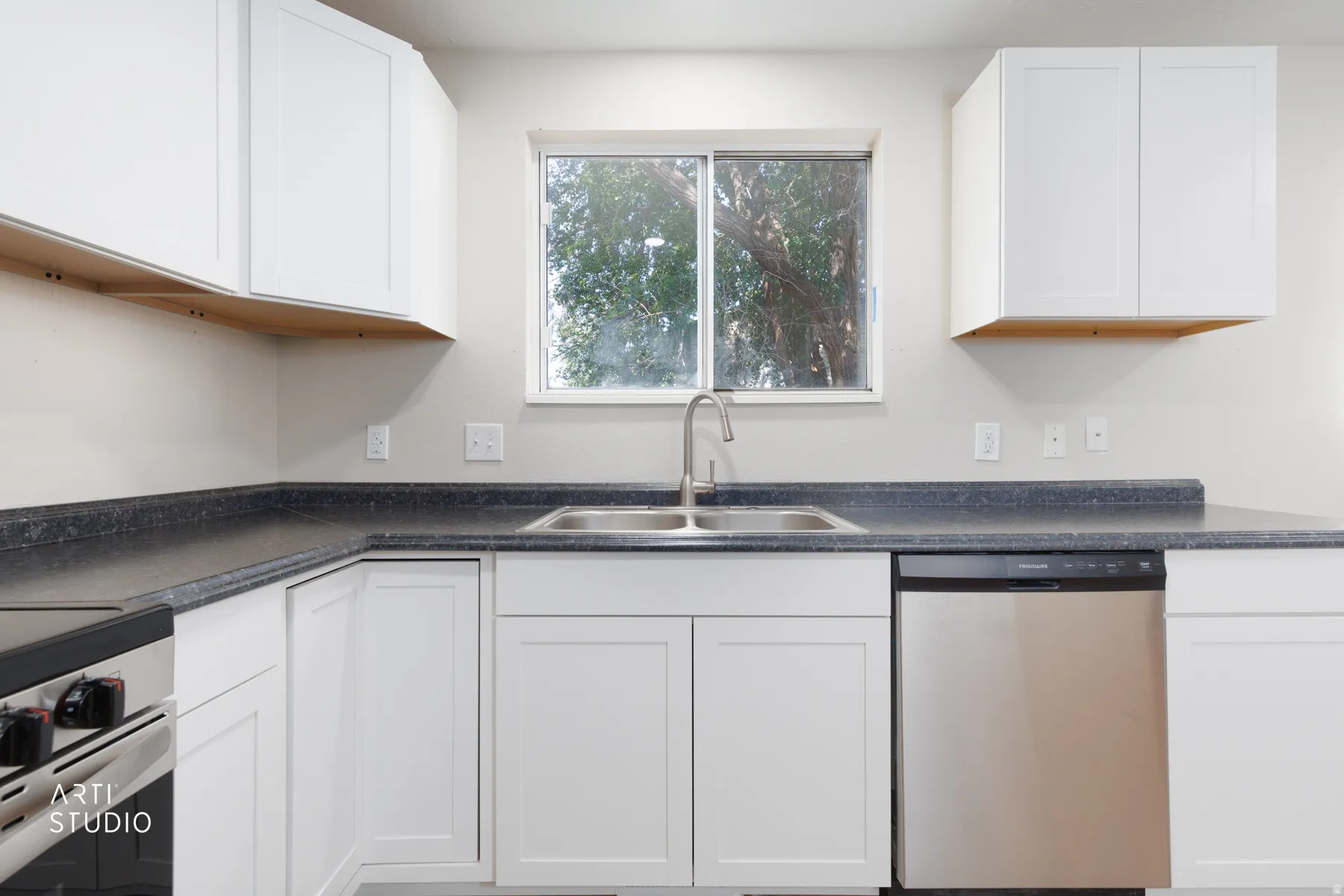 Kitchen featuring white shaker-style cabinetry, dark countertops, a double basin stainless steel sink with a brushed nickel faucet, and a stainless steel dishwasher