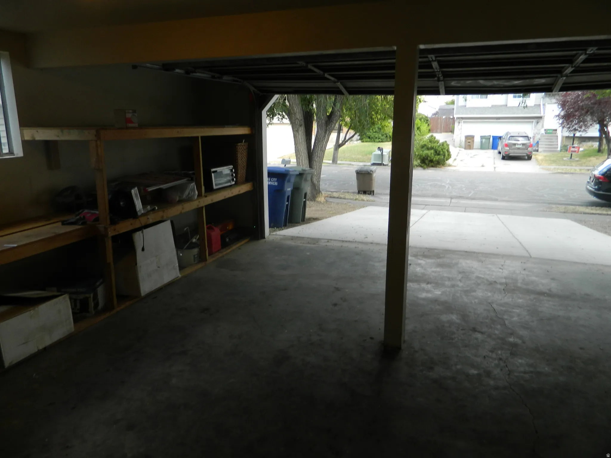 Attached garage with concrete flooring, integrated shelving, and a window