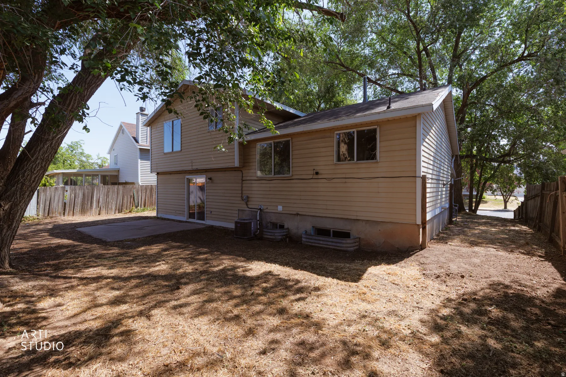 Rear exterior featuring tan siding and a concrete patio