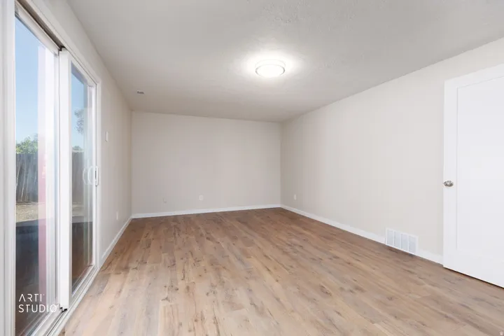 Spacious room with wood-finish flooring and a white sliding glass door