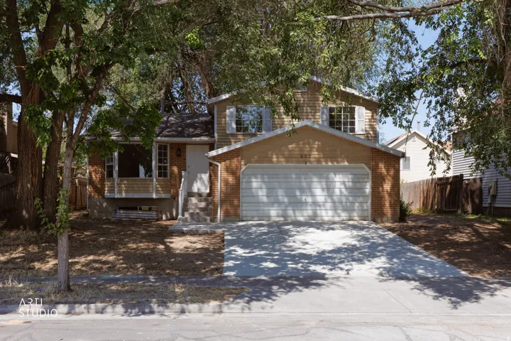 Split-level residence featuring a two-car garage, brick and siding exterior, and mature trees